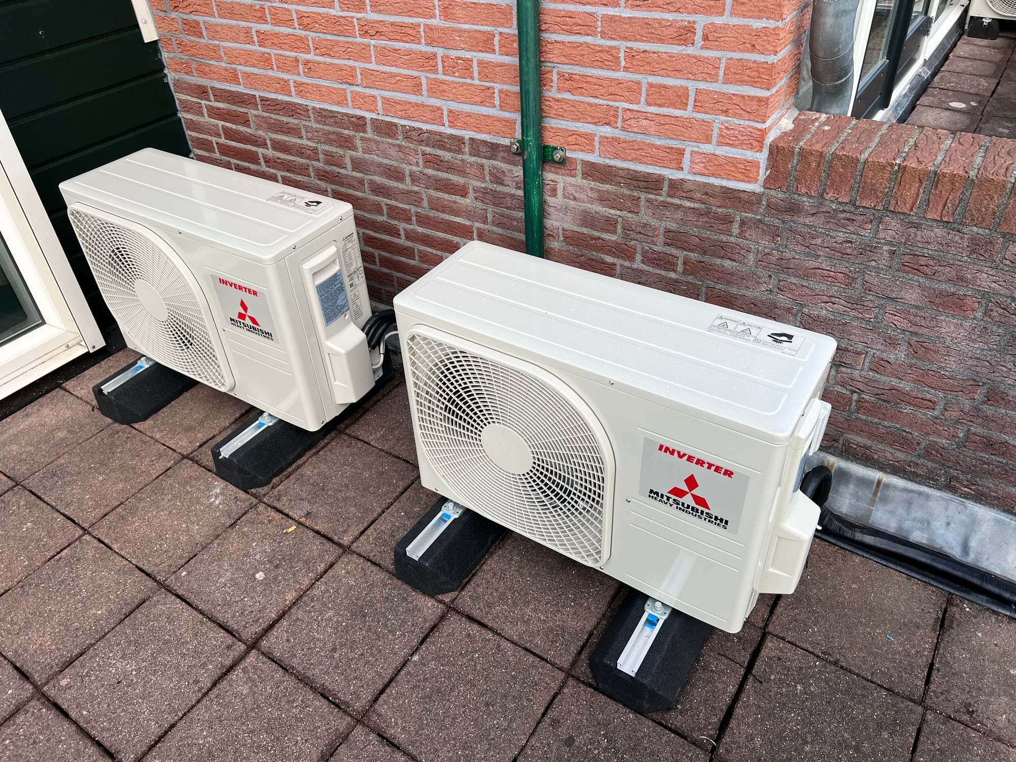 Twee buitenunits op dempers tegen een bakstenen gevel
