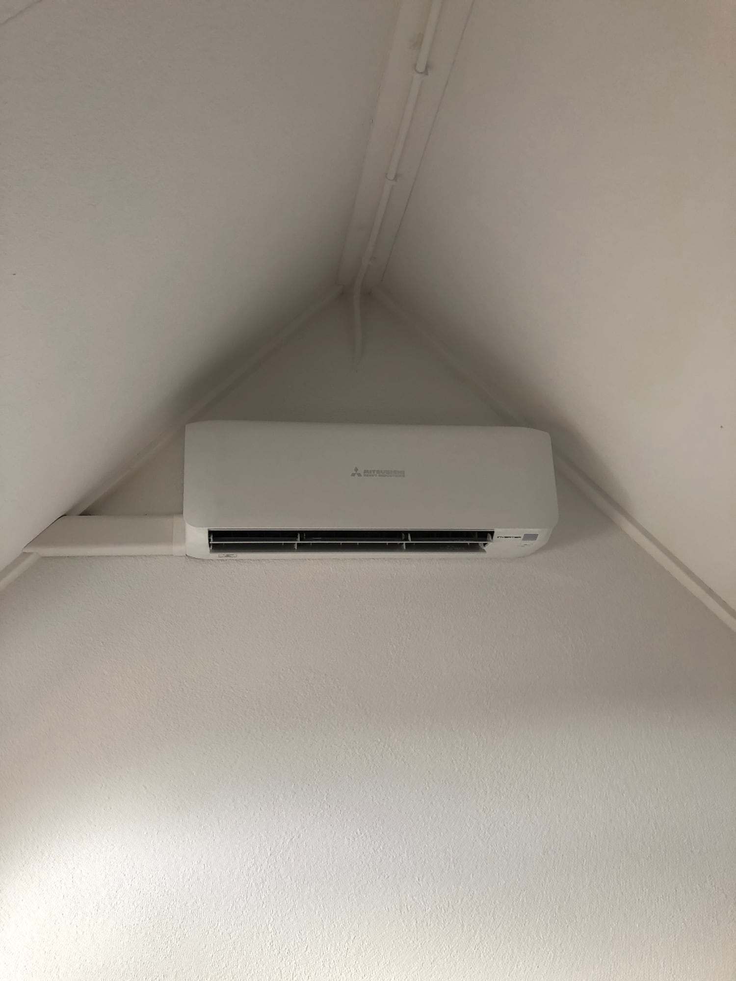 Wit airco-wandmodel hoog in de nok van een zolder